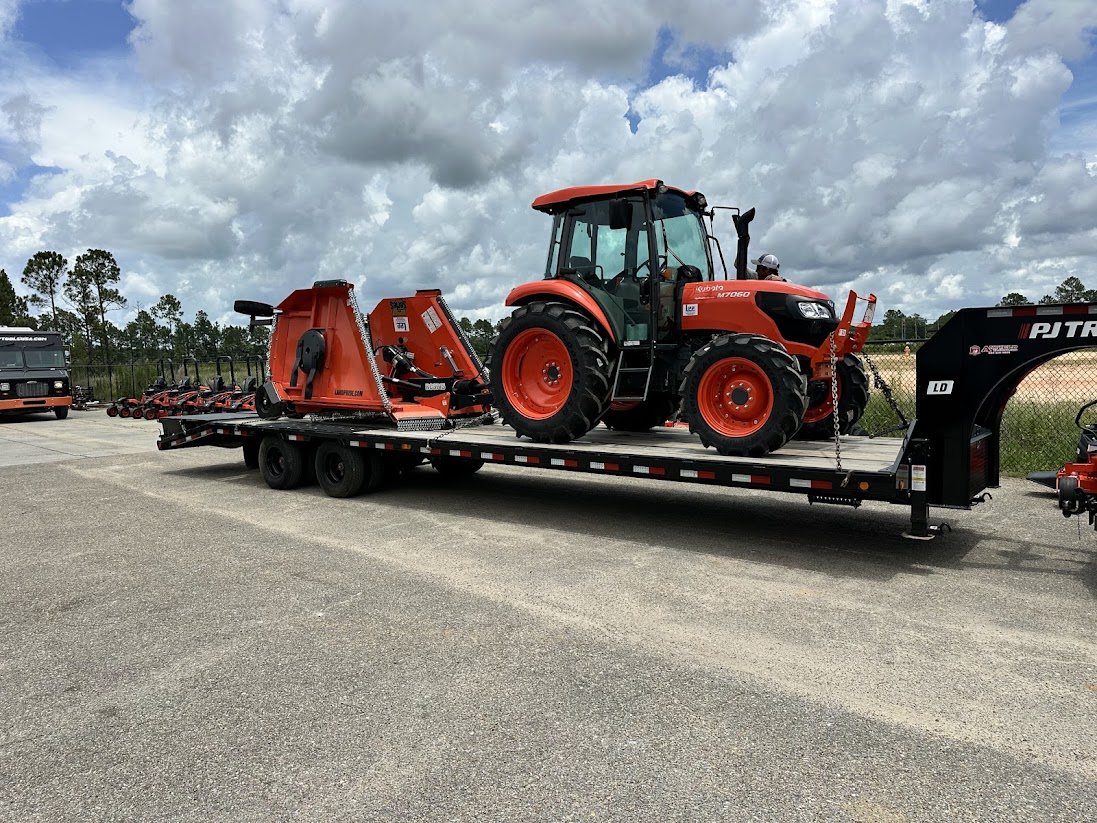 Orange Kubota tractor and rotary mower on a trailer