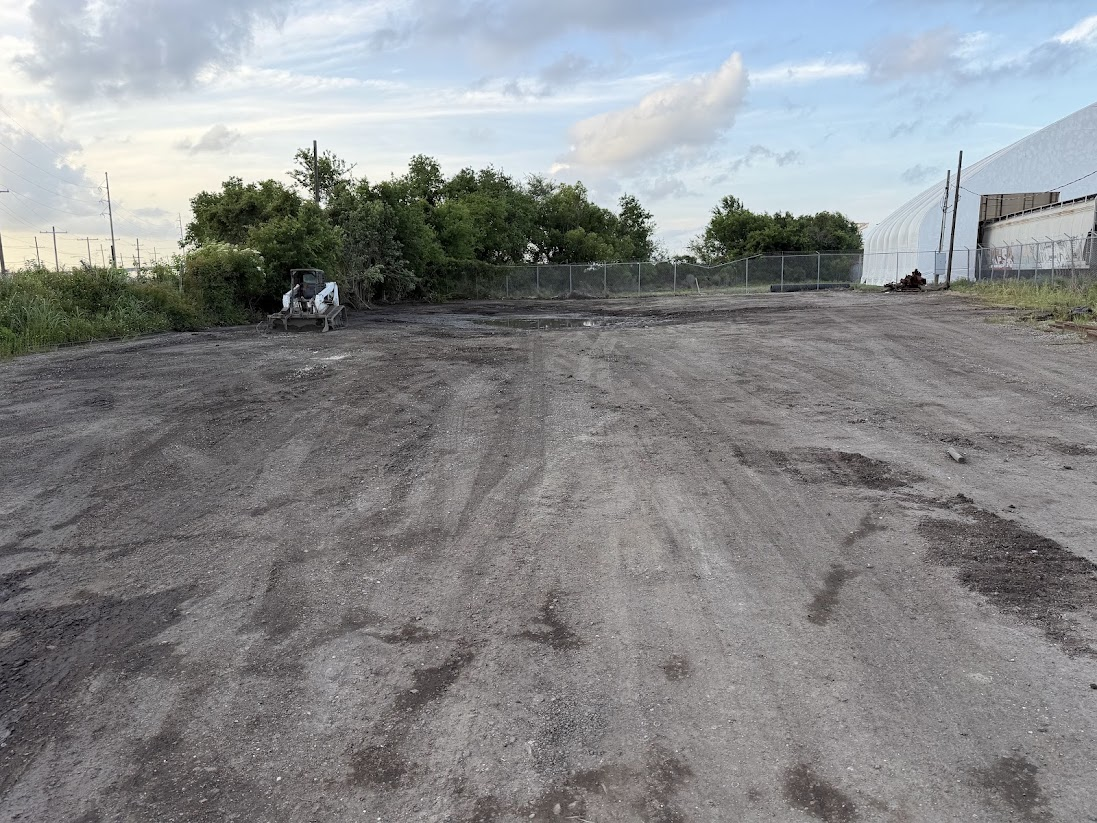 Cleared property with a skid steer beside remaining vegetation